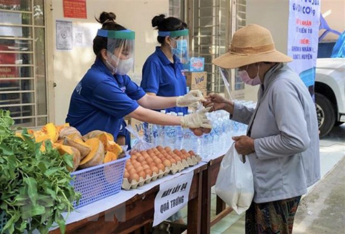 Đoàn viên thanh niên huyện Nhà Bè hỗ trợ người dân mua sắm thực phẩm tại siêu thị 2.000 đồng ở xã Hiệp Phước. (Ảnh: Hồng Giang/TTXVN)