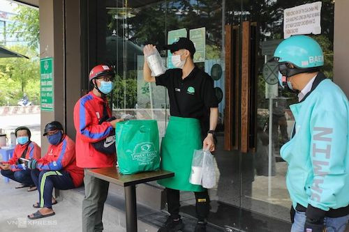 Shipper chờ nhận hàng tại một tiệm cà phê trên đường Nguyễn Hữu Thọ, quận 7 ngày 16/9. Ảnh: Quỳnh Trần