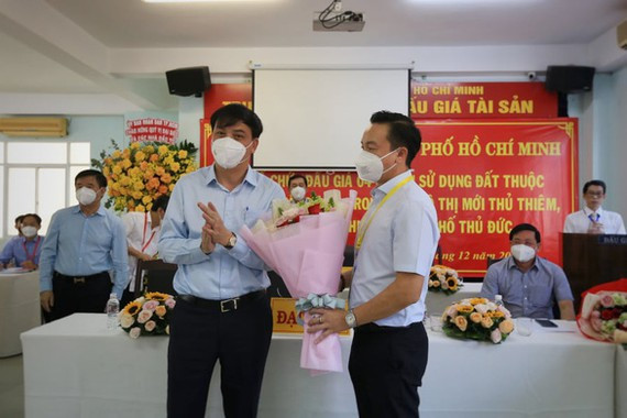 Ông Lê Hòa Bình, Phó chủ tịch UBND TP, trao hoa chúc mừng Công ty cổ phần Dream Republic trúng đấu giá.